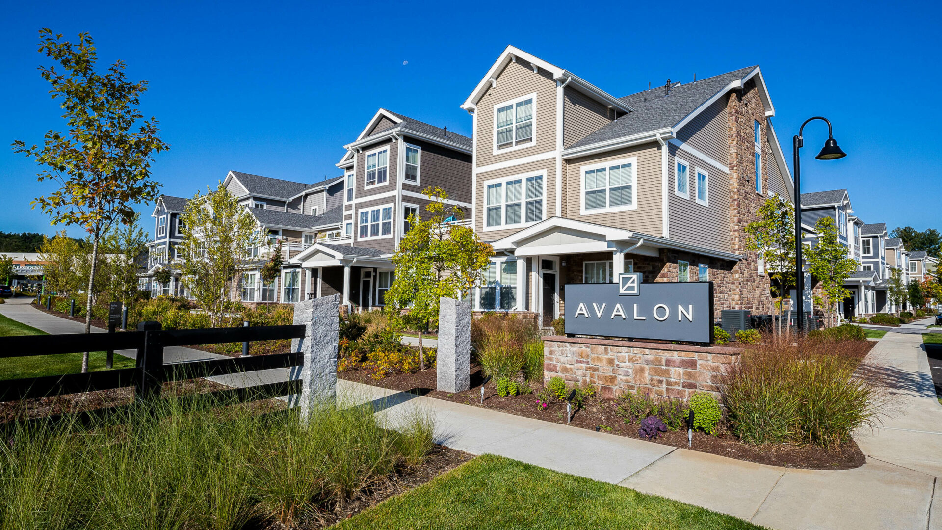 Stone veneer Avalon sign with landscaped flower beds. Commercial hardscape and landscape project by Dex by Terra.