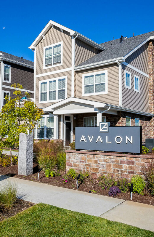 Stone veneer Avalon sign with landscaped flower beds. Commercial hardscape and landscape project by Dex by Terra.