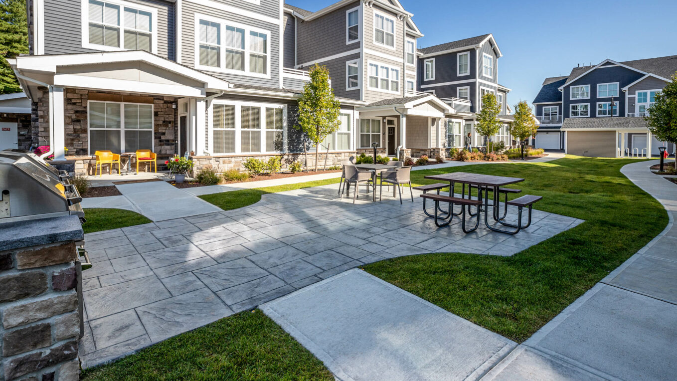 Stamped concrete patio with outdoor kitchens in a luxury apartment amenity area in MA. Commercial hardscape by Dex by Terra.