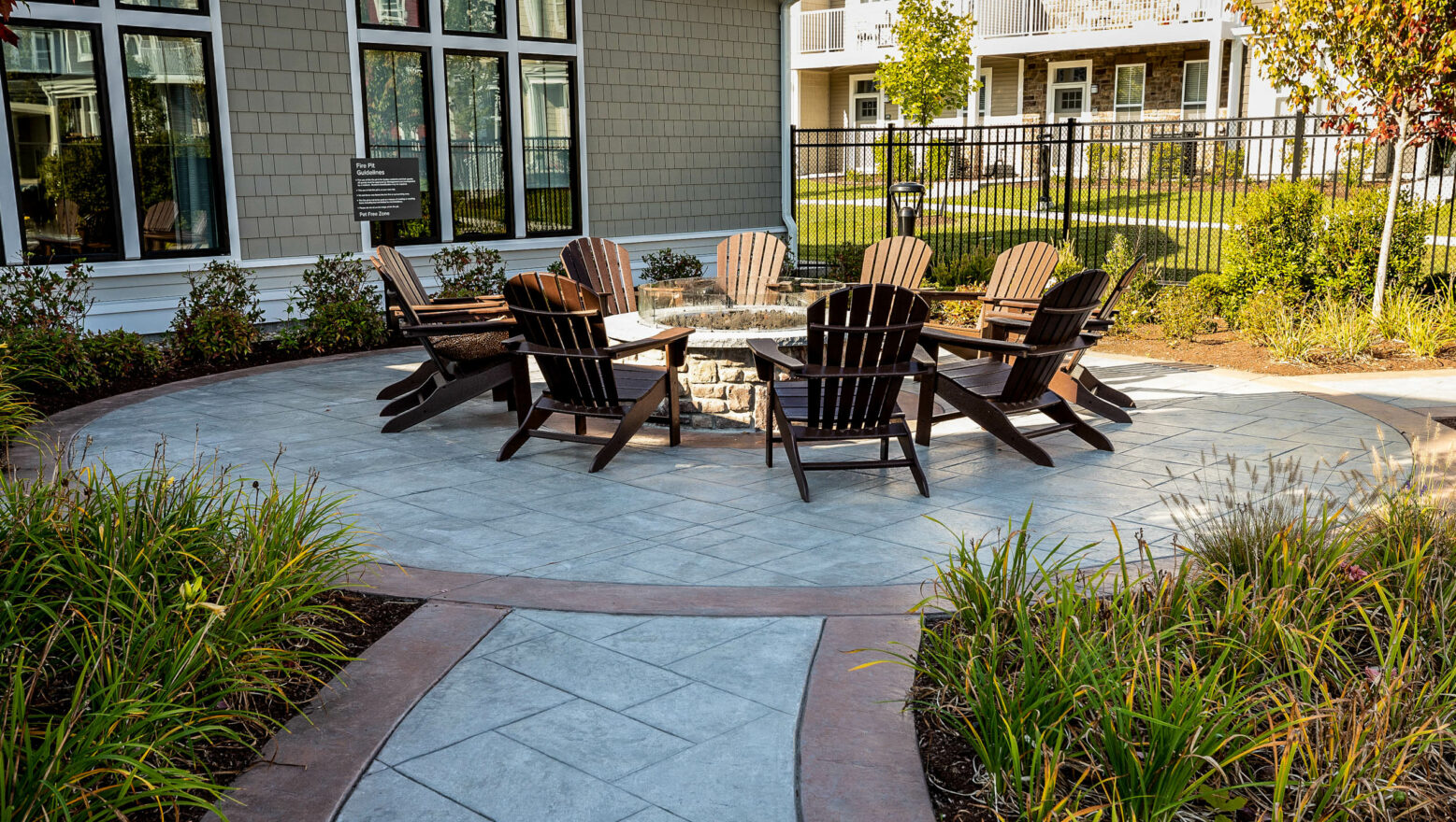 Chairs around a fire pit with stamped and colored concrete patio. Dex by Terra commercial hardscape in MA.