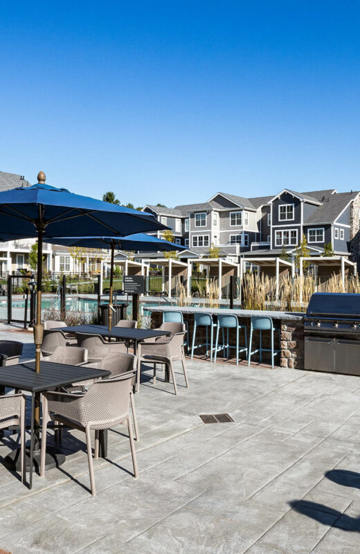 Outside BBQ and stools by a pool.