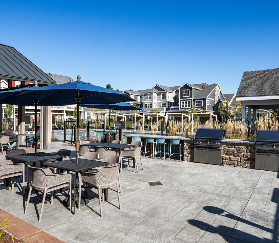 Outside BBQ and stools by a pool.