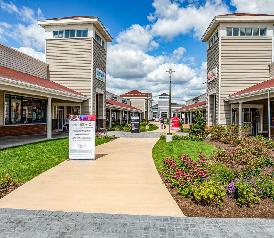 Wrentham Outlets shopping center with concrete & paver walkways. Commercial hardscape & landscape project by Dex by Terra.