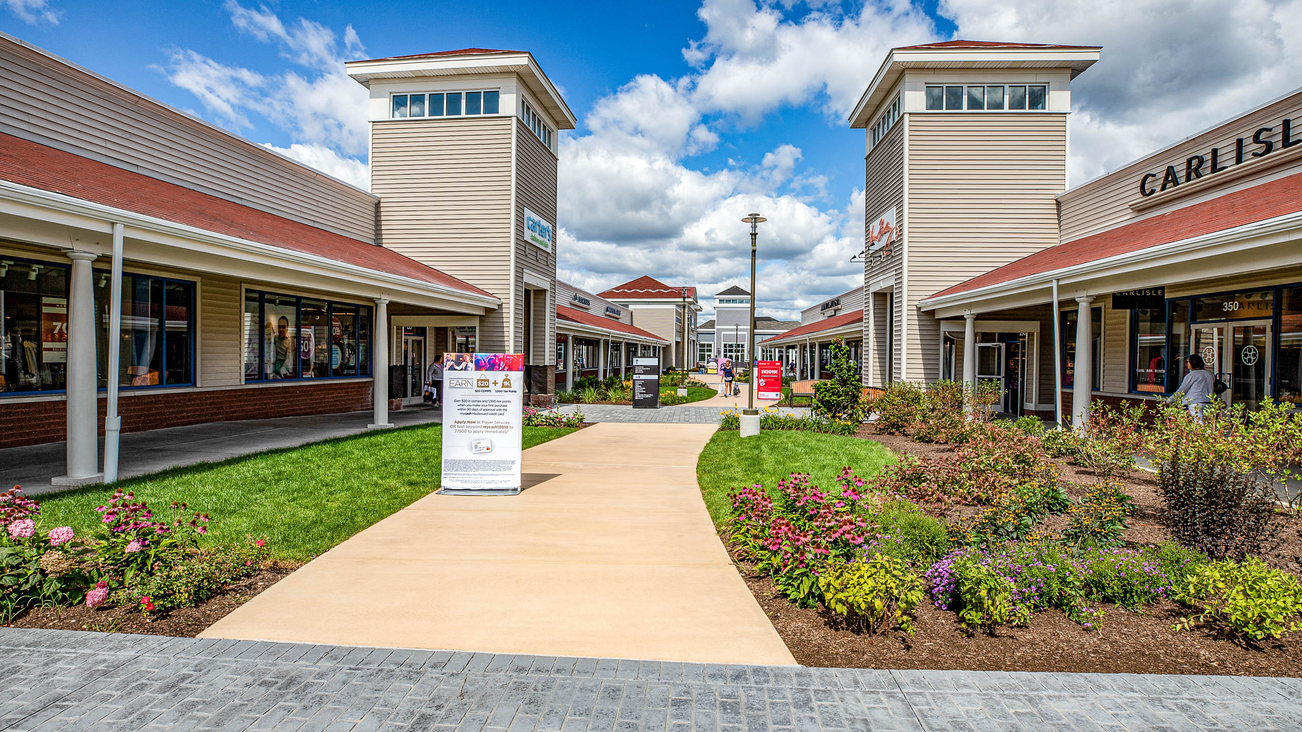 Wrentham Outlets shopping center with concrete & paver walkways. Commercial hardscape & landscape project by Dex by Terra.