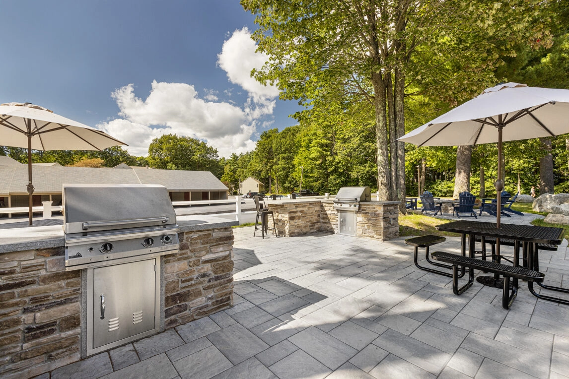 Grill stations and seating in the resident amenity area at Cranmore Ridge Apartments in Concord, NH. Dex by Terra Hardscape.