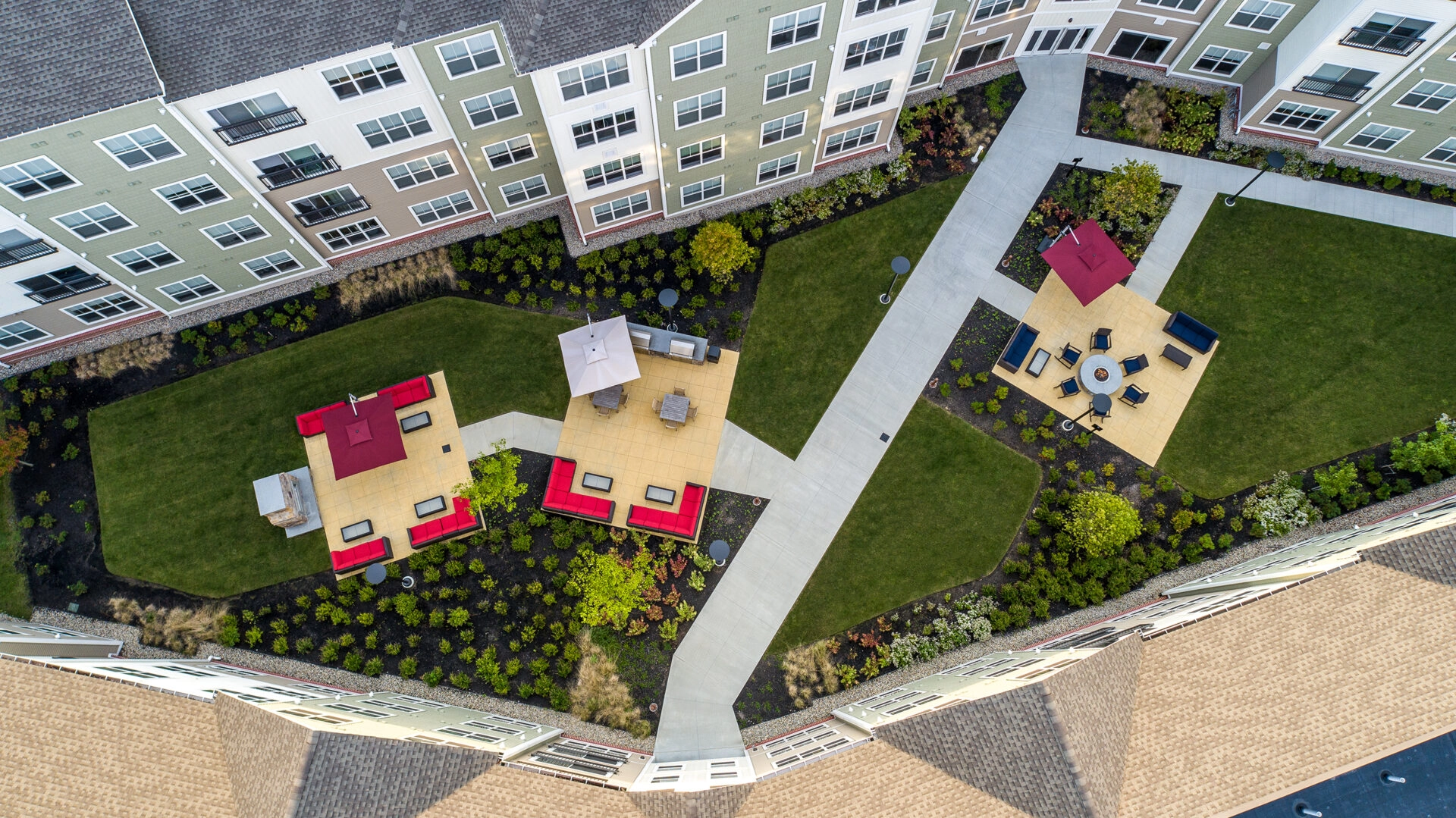 Eli Apartments courtyard drone view. Outdoor kitchen areas, and fire pit area. Dex by Terra Commercial Hardscape Project.