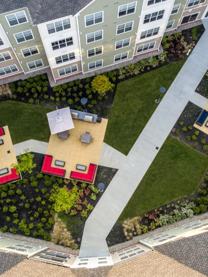 Eli Apartments courtyard drone view. Outdoor kitchen areas, and fire pit area. Dex by Terra Commercial Hardscape Project.