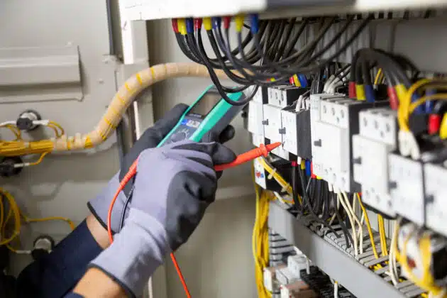 Electrician engineer tests electrical installations and wires on relay protection system.