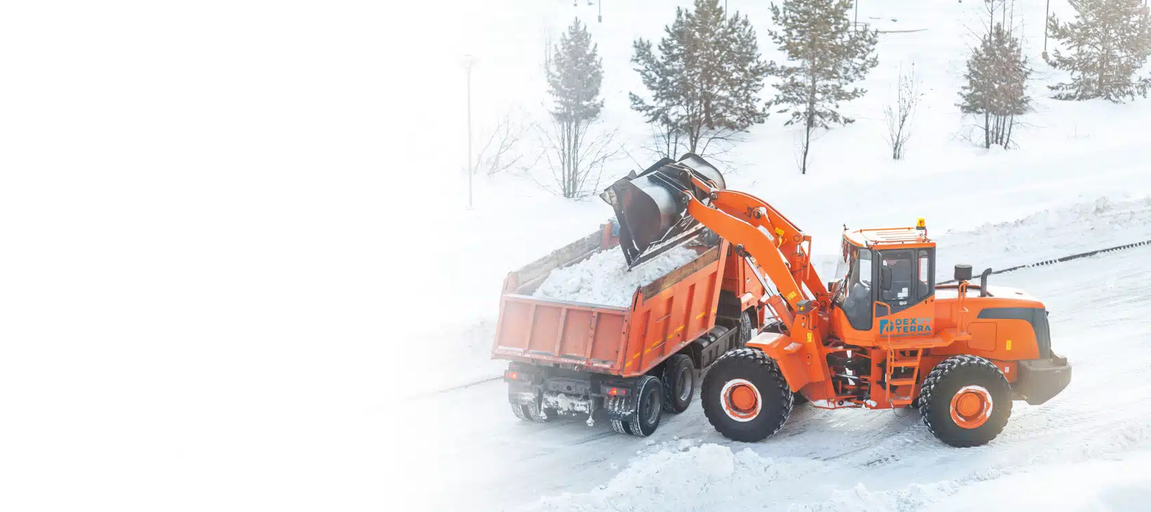 Dex By Terra loader loading snow into dump truck at a commercial snow removal job site.